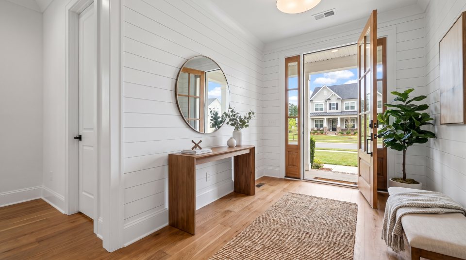 A bright entry hall with painted shiplap, a console table and an open front door letting in daylight