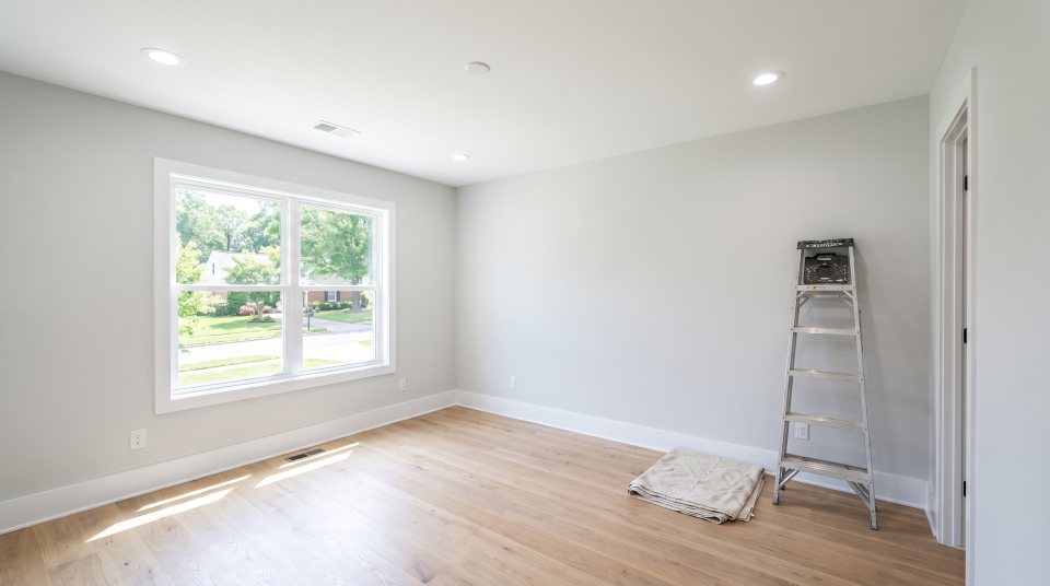 An empty room with a step ladder and drop cloth set up for painting