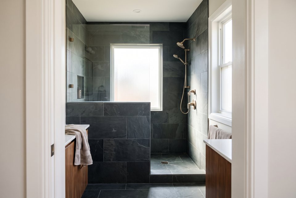 A slate-tiled walk-in shower with a tiled half wall