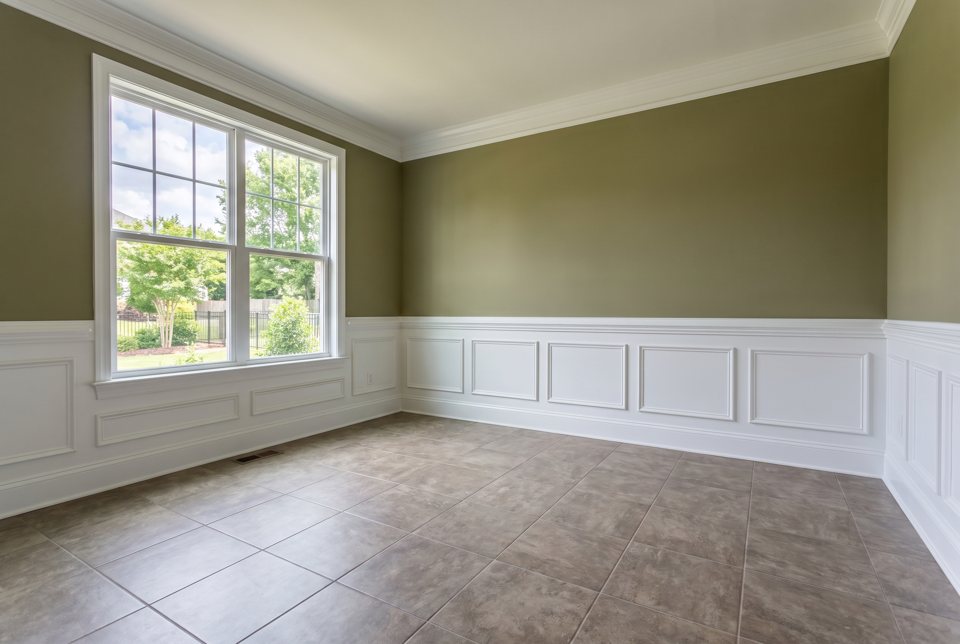 A dining room with a new ceramic tile floor and painted wainscot
