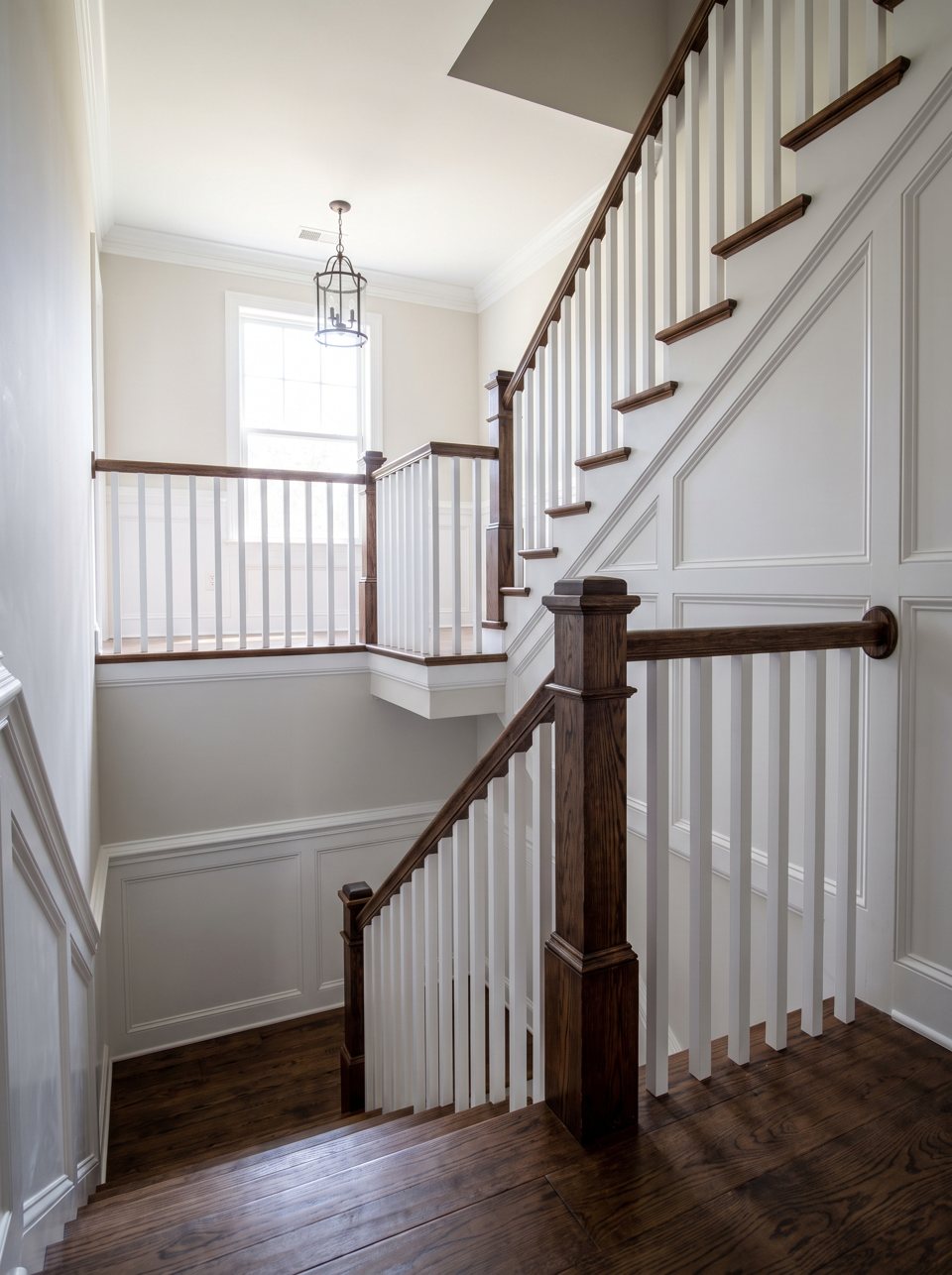 A finished staircase with a dark oak rail, white balusters and wainscot