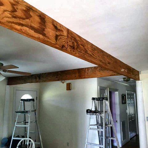 A single stained timber beam fixed across a ceiling in a room being repainted