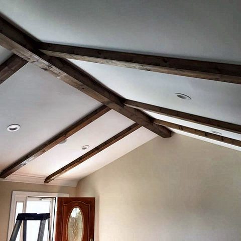 A vaulted ceiling with dark stained timber beams and a painters' ladder below