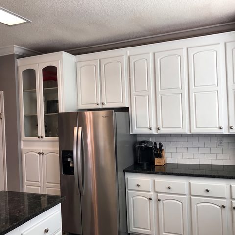 A corner of a finished white kitchen with a tall cabinet run and subway-tile backsplash