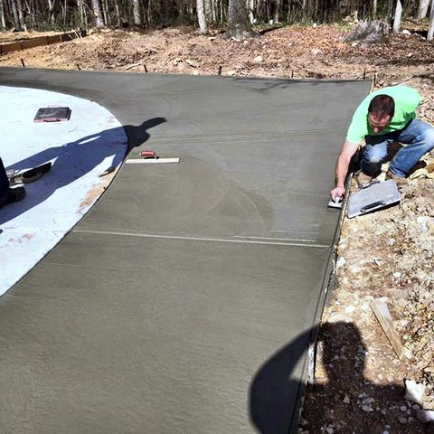 A member of the crew hand-finishing freshly poured concrete on a new pool deck